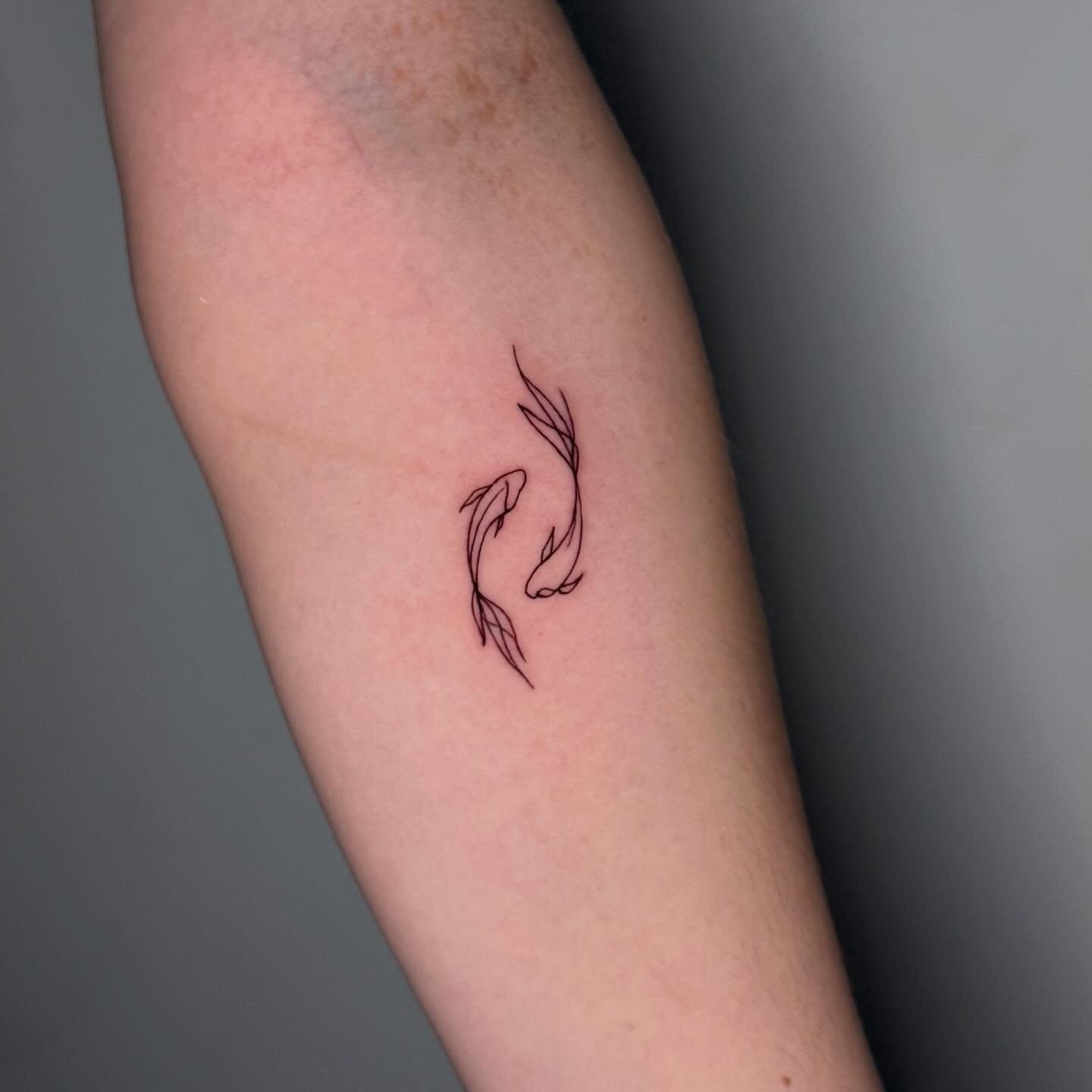 Tatuaje fine line de dos peces koi en círculo