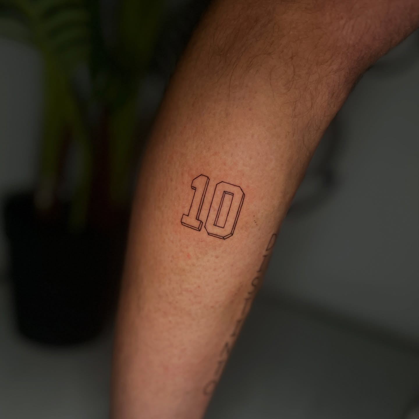 Tatuaje fine line del número 10 estilo dorsal
